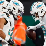Miami Dolphins safety Jevon Holland (8) celebrates with teammates after running an interception back for a touchdown against the New York Jets during the second quarter of an NFL football game, Friday, Nov. 24, 2023, in East Rutherford, N.J. (AP Photo/Noah K. Murray)